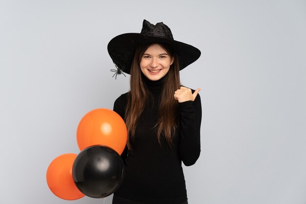 Junges Mädchen mit schwarzem Hut und schwarzem Kleid, das Ballons hält