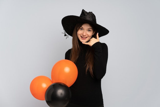 Junges Mädchen mit schwarzem Hut und schwarzem Kleid, das Ballons hält