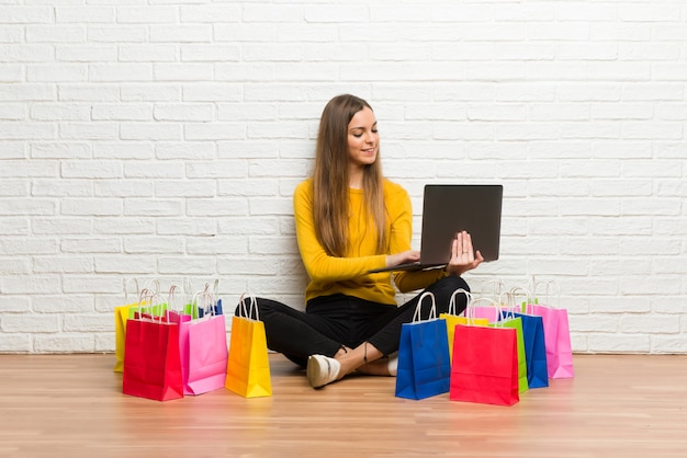 Junges Mädchen mit vielen Einkaufstüten mit Laptop