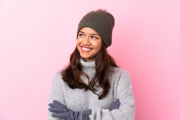 Junges Mädchen mit Winterhut über der rosa Wand, die zur Seite schaut