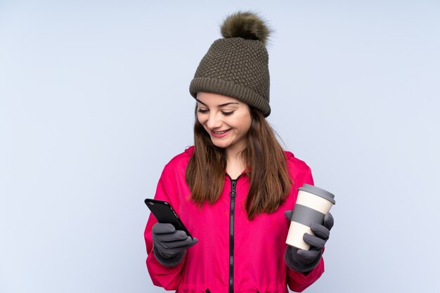 Junges Mädchen mit Wintermütze lokalisiert auf Blau