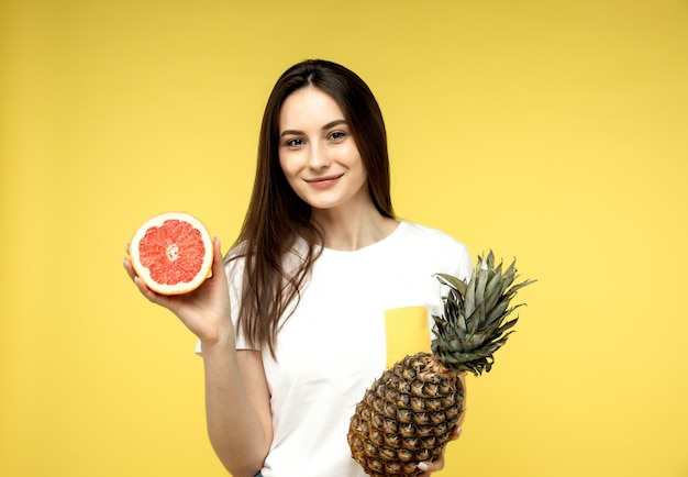 junges Mädchen posiert mit Grapefruithälfte und einer Ananas