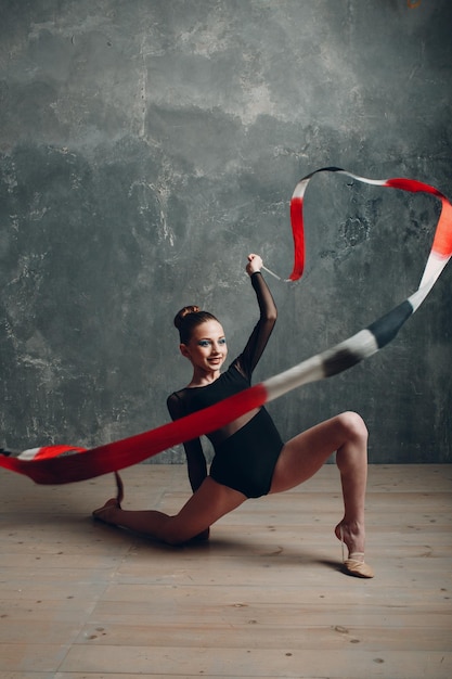 Junges Mädchen professionelle Turnerin rhythmische Gymnastik mit Band im Studio