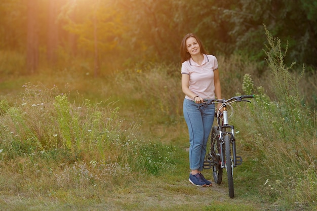 Junges Mädchen reitet auf dem Fahrrad im Wald, Sonnenlicht