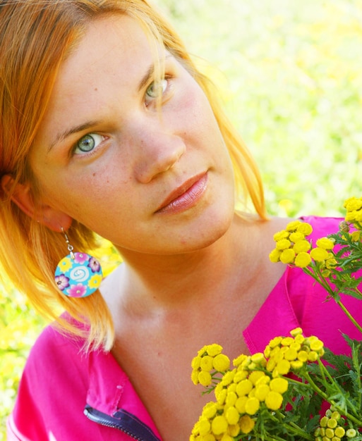 Foto junges mädchen riecht gelbe blumen auf dem feld