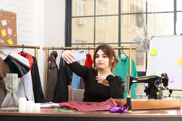 Junges Mädchen sitzt im Atelier und macht Selfie mit ihrem Handy