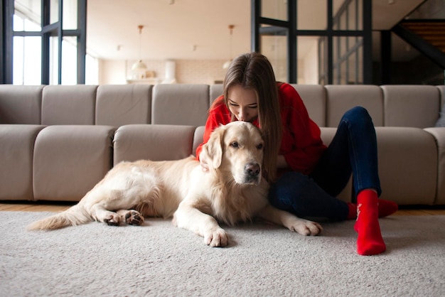 Junges Mädchen spielt mit Hund der Rasse Golden Retriever zu Hause auf dem Boden, Frau mit Haustier zusammen