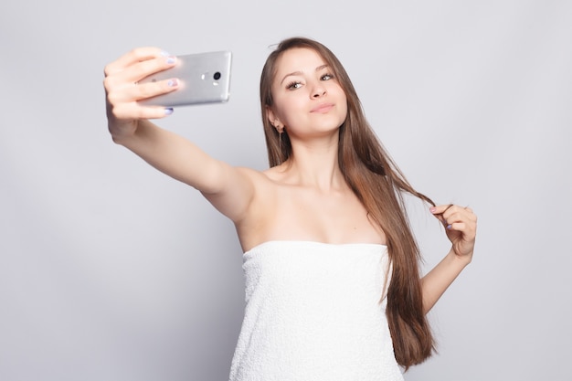 Junges Mädchen trägt Handtuch und macht ein Selfie