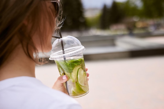 Junges Mädchen trinkt bei sonnigem Wetter einen kühlen Matcha-Cocktail