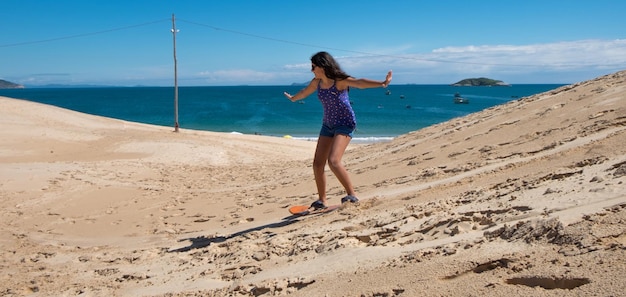 Junges Mädchen übt Sandbord in den Dünen von Florianopolis, Brasilien