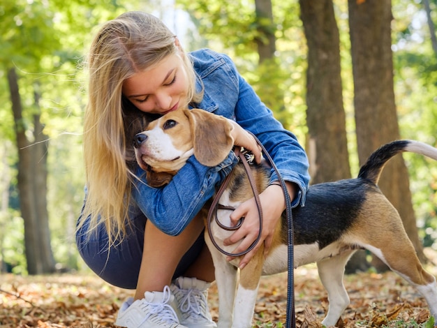 Junges Mädchen umarmt einen Beagle-Hund im Herbstpark