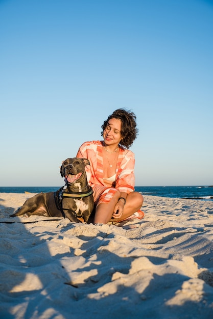 Junges Mädchen und Pitbull-Hund in einem Moment der Zuneigung am Strand von Saquarema in Rio de Janeiro. Sonnenuntergang.