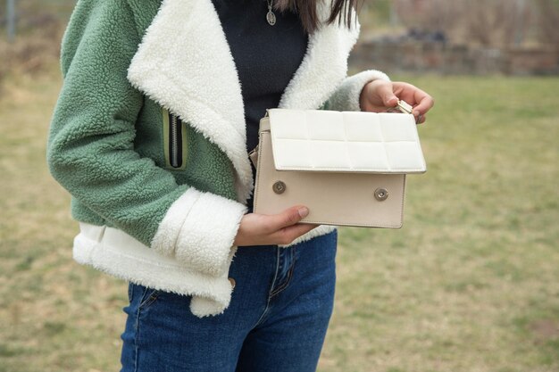 Junges Mädchen zeigt Handtasche im Freien