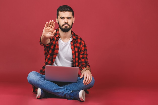 Junges männliches Studentenmodell, das auf Boden sitzt