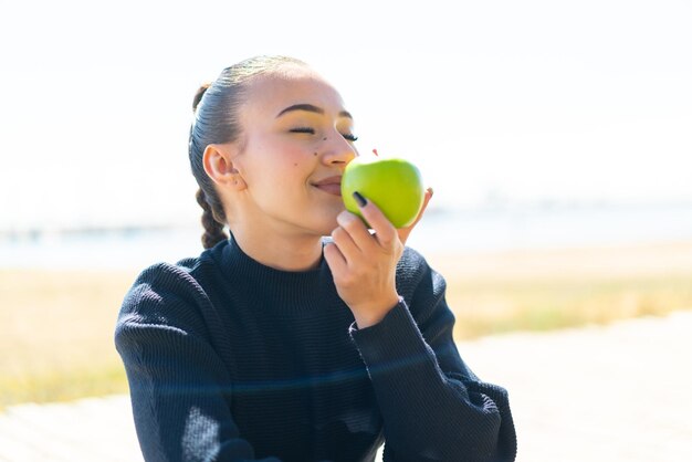 Junges marokkanisches Mädchen im Freien mit einem Apfel