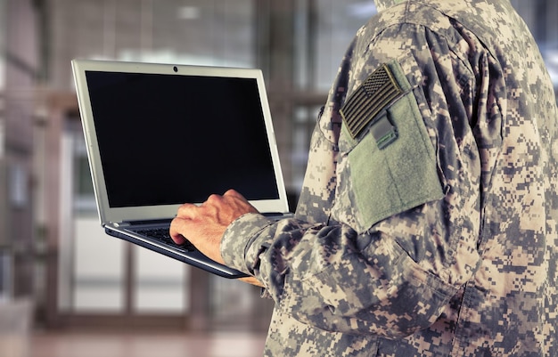 Foto junges militärsoldat-mannporträt mit laptop auf hintergrund