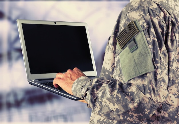 Foto junges militärsoldaten-mannporträt mit laptop auf hintergrund