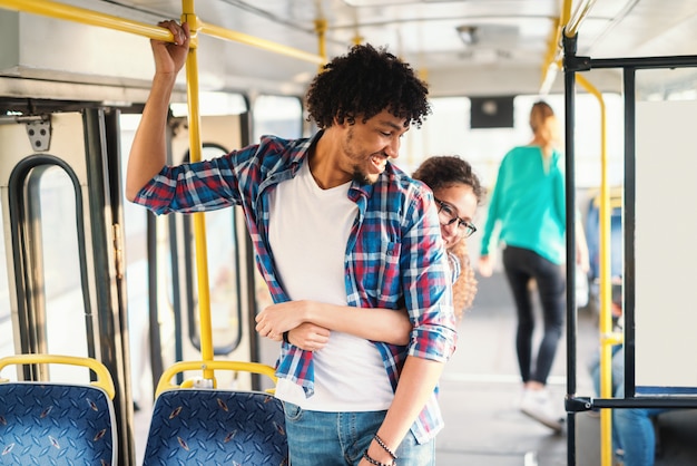 Junges multikulturelles Paar, das im öffentlichen Verkehr umarmt.