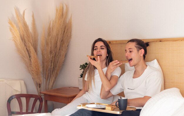 Junges Paar am Morgen beim romantischen Frühstück im Bett am Valentinstag als glückliche Beziehungen