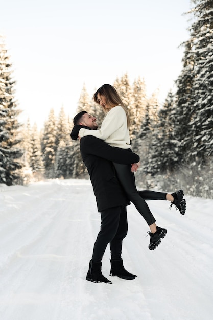 Junges Paar auf dem Schnee im Winter im Park Liebes- und Urlaubskonzept Glückliches Paar, das sich im Winter im Freien umarmt und lacht