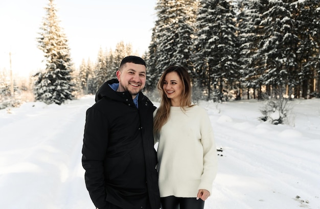Junges Paar auf dem Schnee im Winter im Park Liebes- und Urlaubskonzept Glückliches Paar, das sich im Winter im Freien umarmt und lacht