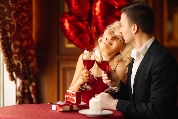 Junges Paar bei einem romantischen Abendessen und einem Toast mit einem Glas Rotwein. Überraschungs- und Liebeskonzept