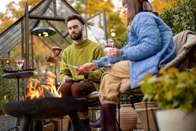 Junges Paar beim Abendessen am Feuer im Hinterhof