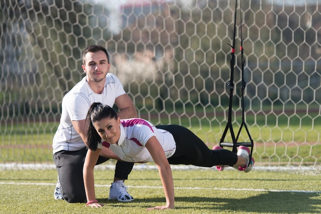 Junges Paar beim Crossfit mit Trx-Fitnessgurten im Stadtparkbereich Training und Training für Ausdauer Gesunder Lebensstil Konzept im Freien