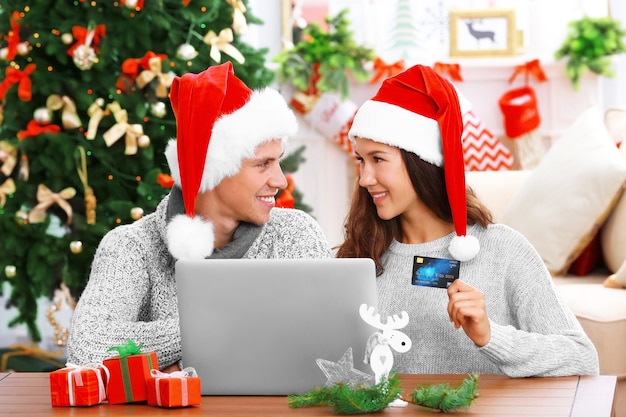 Junges Paar beim Online-Shopping mit Kreditkarte zu Hause zu Weihnachten