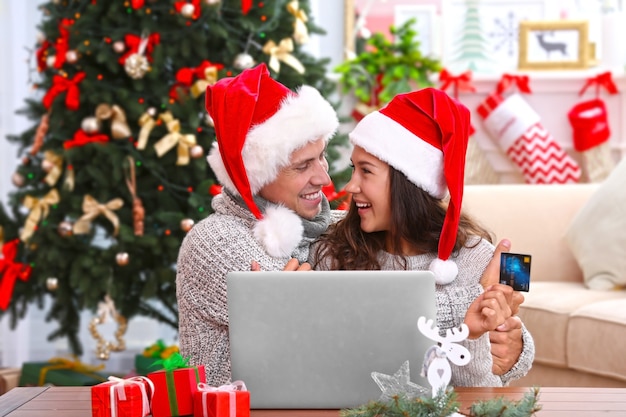 Junges Paar beim Online-Shopping mit Kreditkarte zu Hause zu Weihnachten