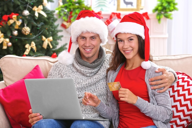 Junges Paar beim Online-Shopping mit Kreditkarte zu Hause zu Weihnachten