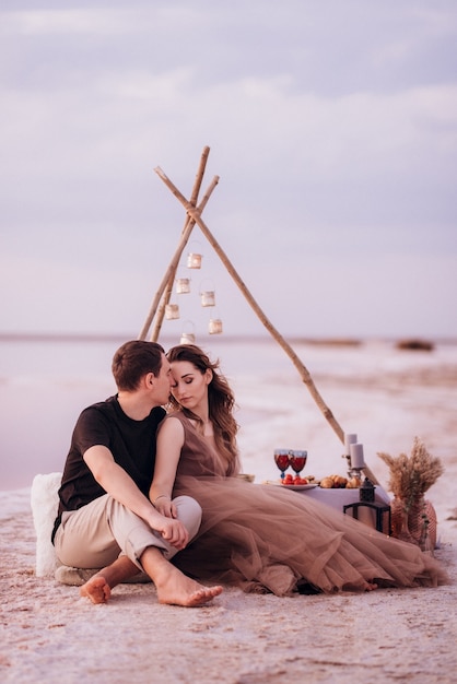 Junges Paar beim Picknick am Strand eines rosa Sees