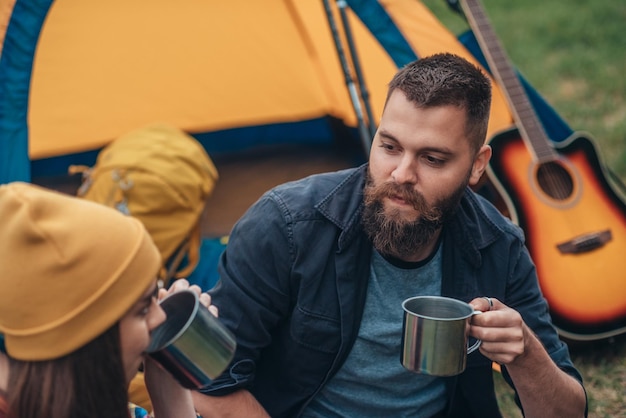 Junges Paar Camper trinkt Kaffee aus Metallbechern in der Natur