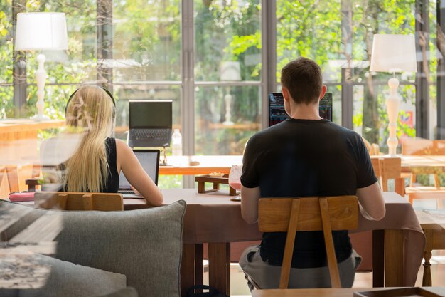 Junges Paar, das an Laptop-Computer im Kaffeehaus arbeitet.