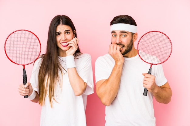 Junges Paar, das Badminton spielt, isolierte beißende Fingernägel, nervös und sehr ängstlich.