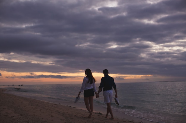 Junges Paar, das den Sonnenuntergang am Strand genießt