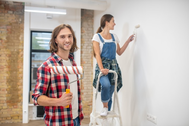 Junges Paar, das eine Wand zusammen in ihrem neuen Haus malt