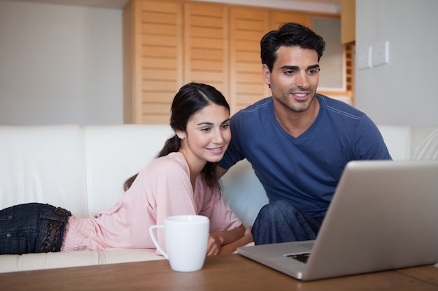 Junges Paar, das einen Laptop beim Trinken eines Kaffees verwendet