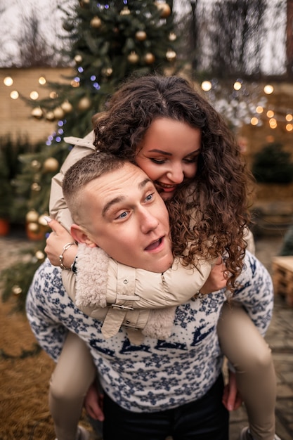 Junges Paar, das in den Weihnachtsgarten nahe dem Weihnachtsbaum geht