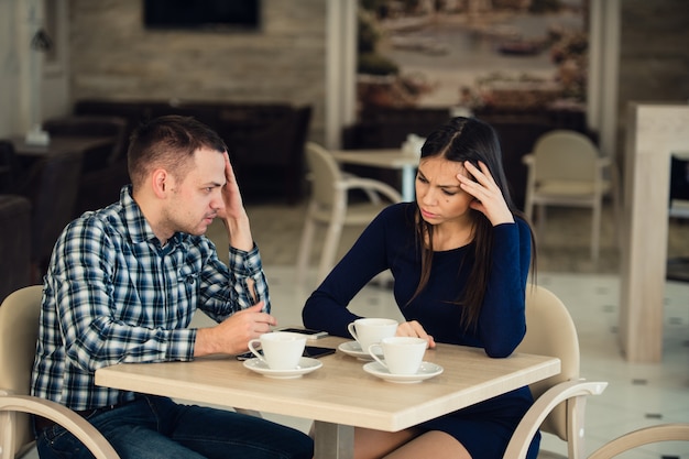 Junges Paar, das in einem Café streitet. Sie hat genug, Freund entschuldigt sich. Beziehungsprobleme.