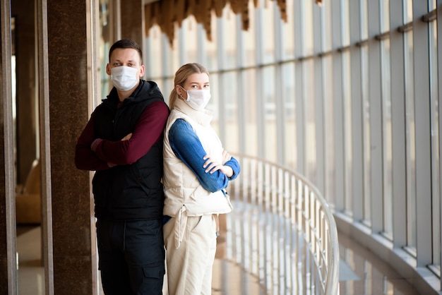 Junges Paar, das medizinische Masken in einer Flughafenlounge trägt