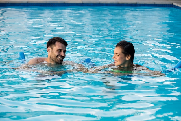 Junges Paar, das mit aufblasbaren Schläuchen im Pool schwimmt