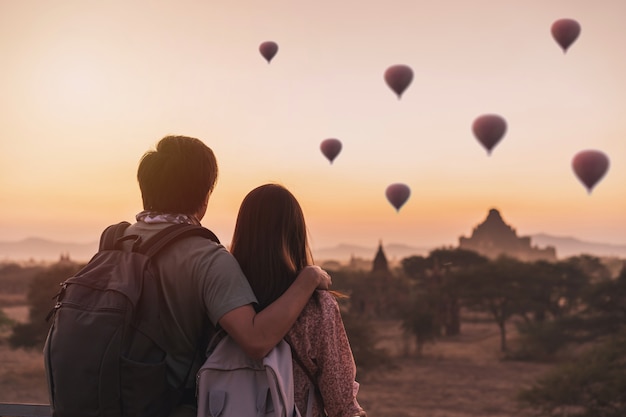 Junges Paar, das mit Luftballons über alte Pagode bei Bagan, Myanmar bei Sonnenaufgang genießt