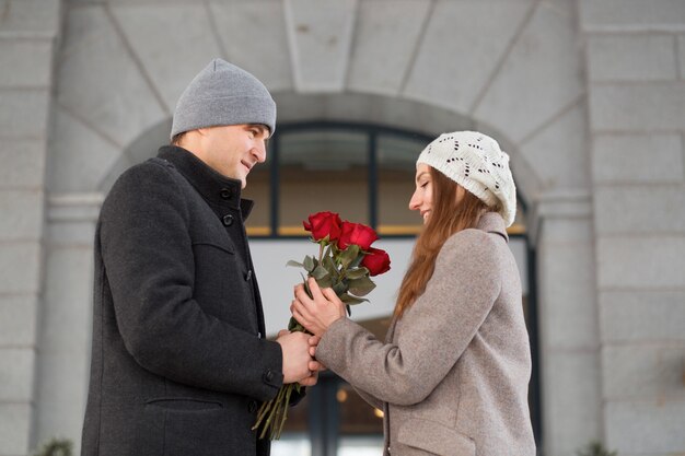 Junges Paar, das mit Rosenstrauß in der Stadt datiert. Valentinstag