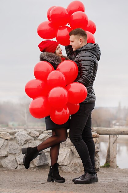 Junges Paar, das mit roten Luftballons geht