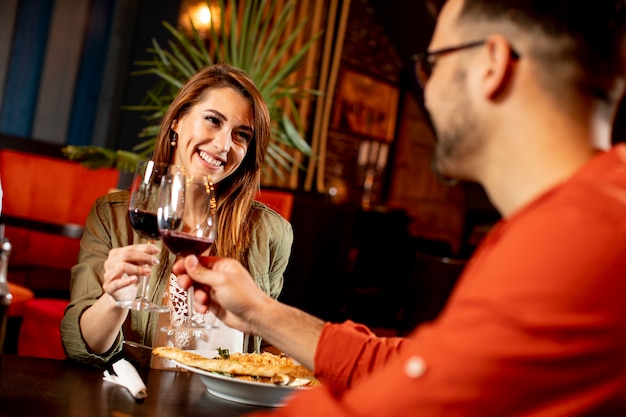 Junges Paar, das Mittagessen im Restaurant mit Gläsern Rotwein genießt