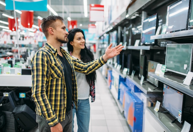 Junges Paar, das Monitor im Supermarkt kauft