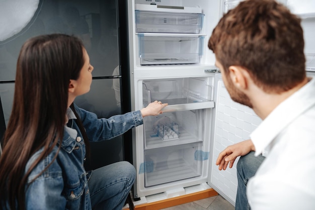 Junges Paar, das neuen Kühlschrank im Haushaltsgerätespeicher auswählt