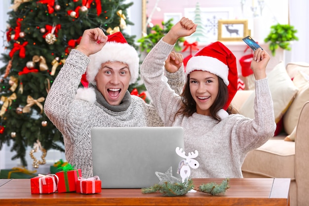 Junges Paar, das online mit Kreditkarte zu Hause für Weihnachten einkauft
