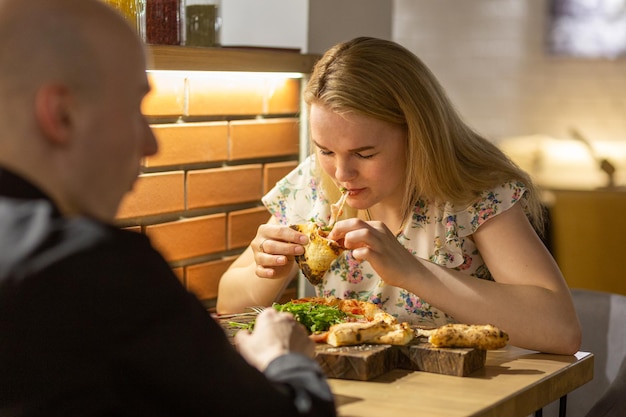 Junges Paar, das Pizza genießt, während es in der Pizzeria sitzt